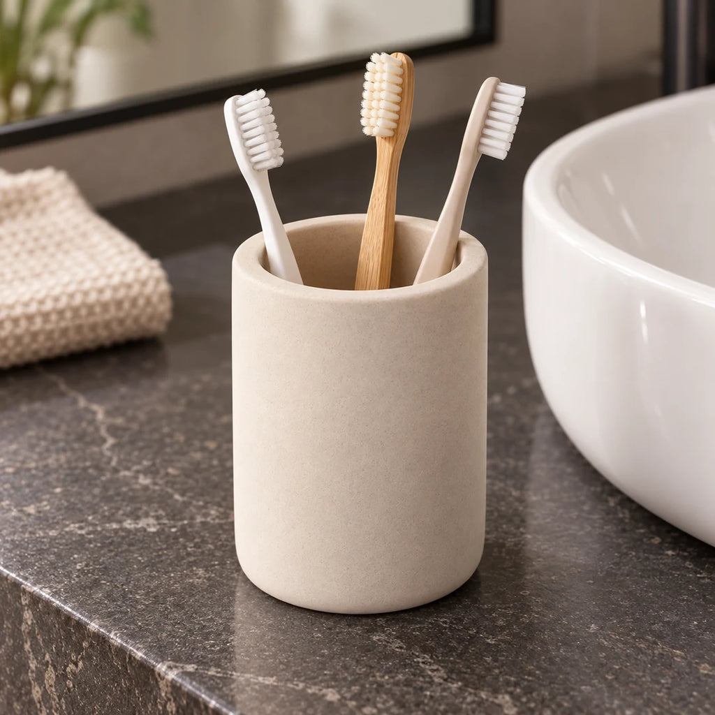 rois brosses à dents rangées dans un gobelet en diatomite beige sur un meuble de salle de bain