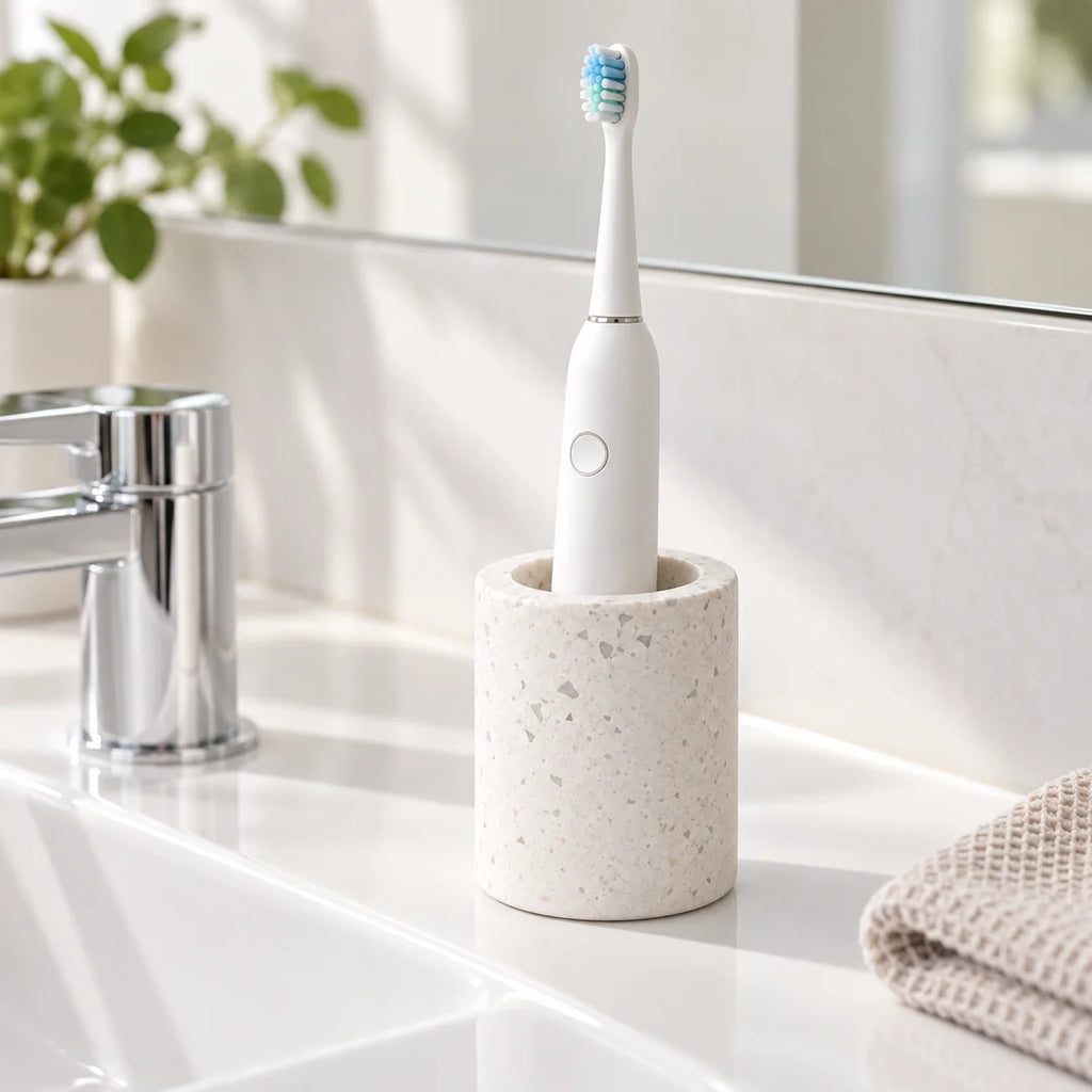Une brosse à dents électrique blanche dans le support Terrazzo Fall, posé près d’un lavabo