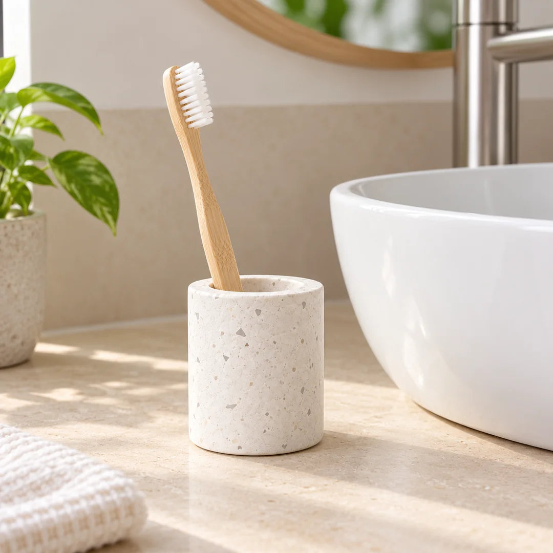 Une brosse à dents classique en bambou dans le support Terrazzo Fall, posé près d’un lavabo.