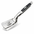 Vue de détail de la spatule pince 2-en-1 en acier inoxydable poli avec un manche ergonomique noir et un verrou coulissant gris. L'ustensile est présenté sur fond blanc.